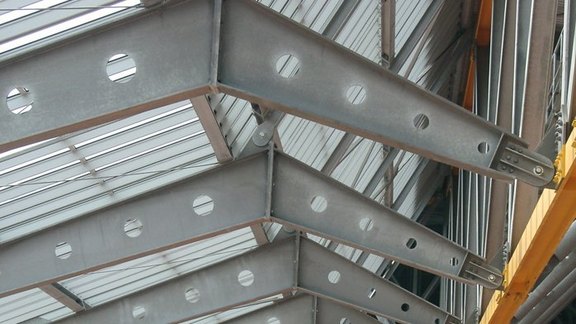 Produktbroschüre BauStatik Stahlbau Titel der Produktbroschüre BauStatik - Stahlbau. Zu sehen ist sind mehrere Stahlträger einer Stadionüberdachung.